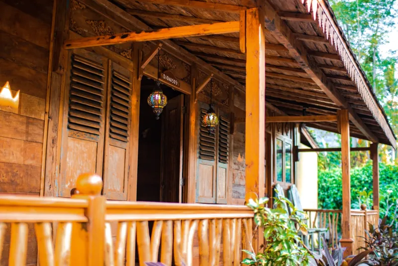 A carved teak cottage veranda with hanging lanterns